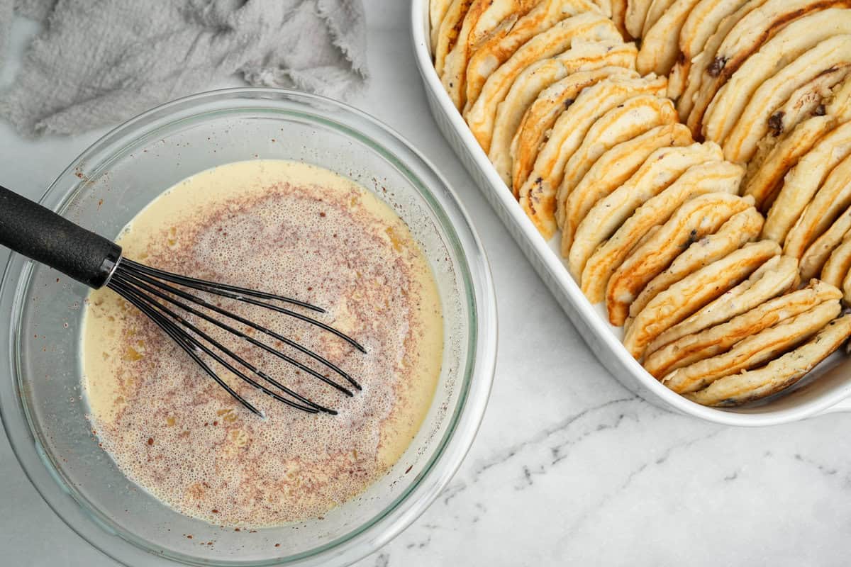 This overnight Pancake Casserole is cozy, decadent, and perfect for slow weekend mornings or holiday brunch. Super easy to make! Custard filling in a bowl being whisked