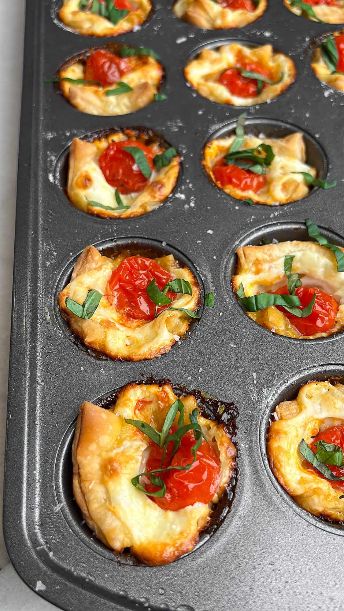 These easy caprese bites combine the fresh flavors of cherry tomatoes, mozzarella, and basil in a warm, flaky crust. Caprese bites in a mini muffin tin.