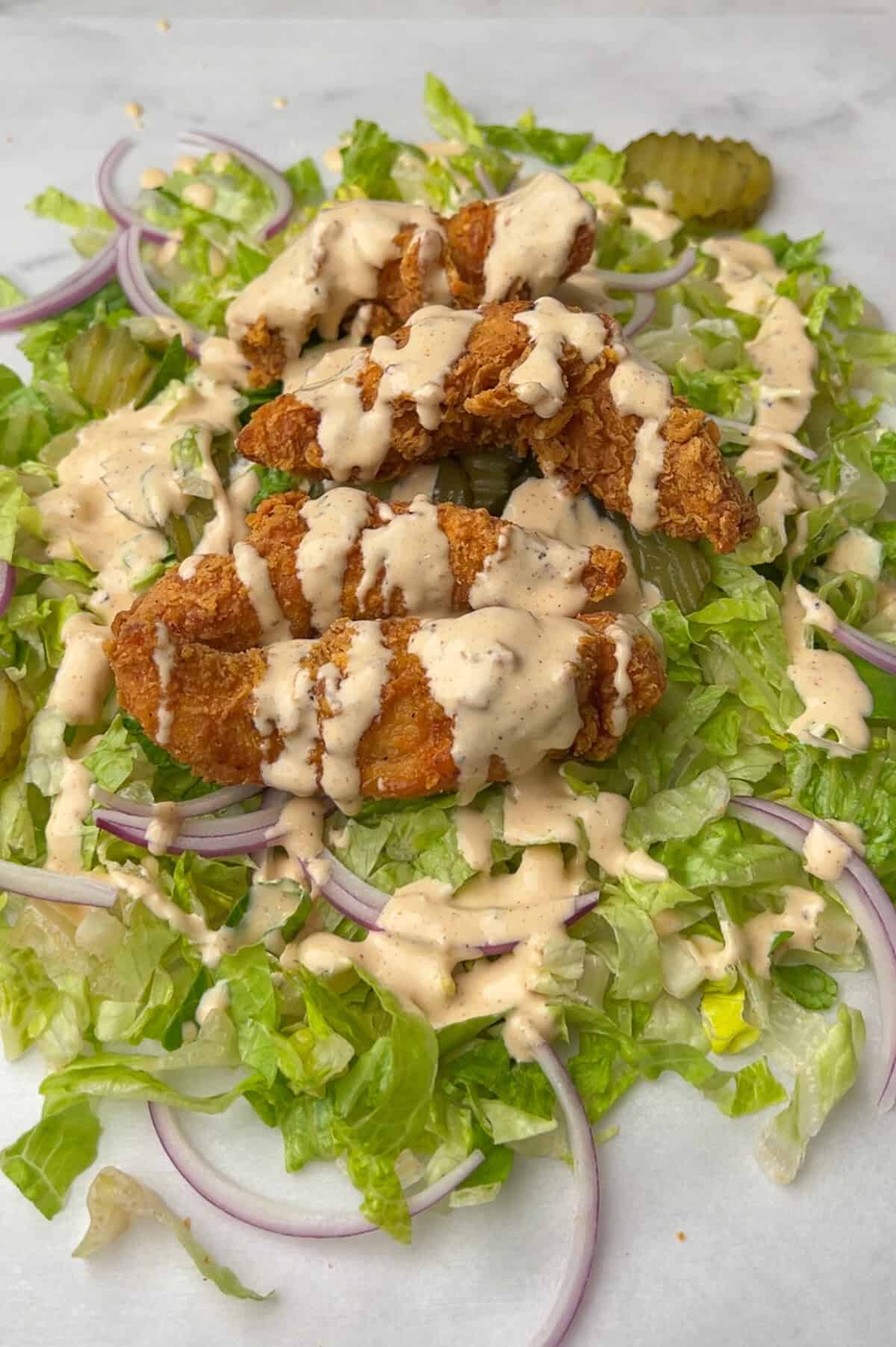 chopped chicken sandwich ingredients on a cutting board with sauce drizzled