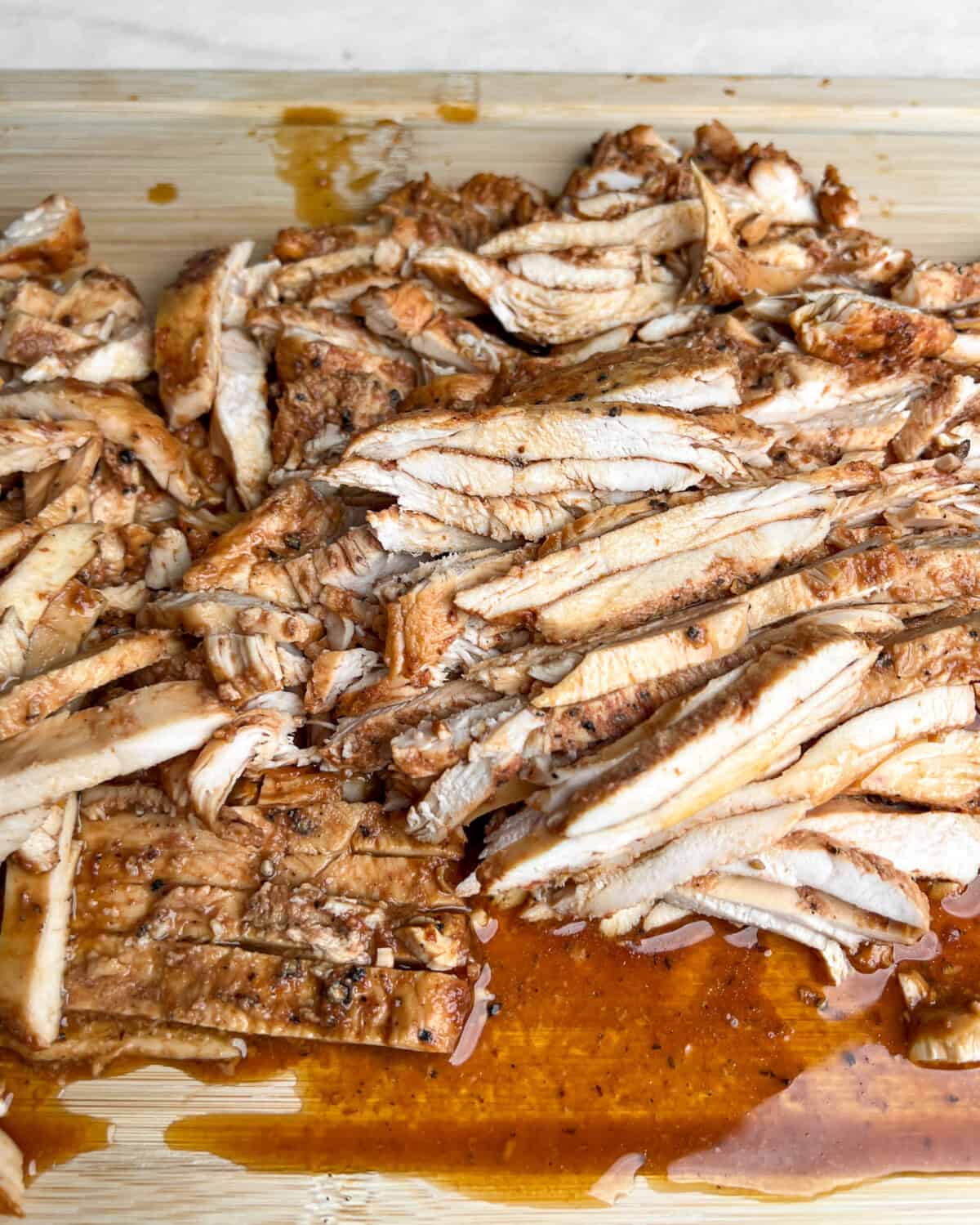 sliced chicken and it's juices on a cutting board