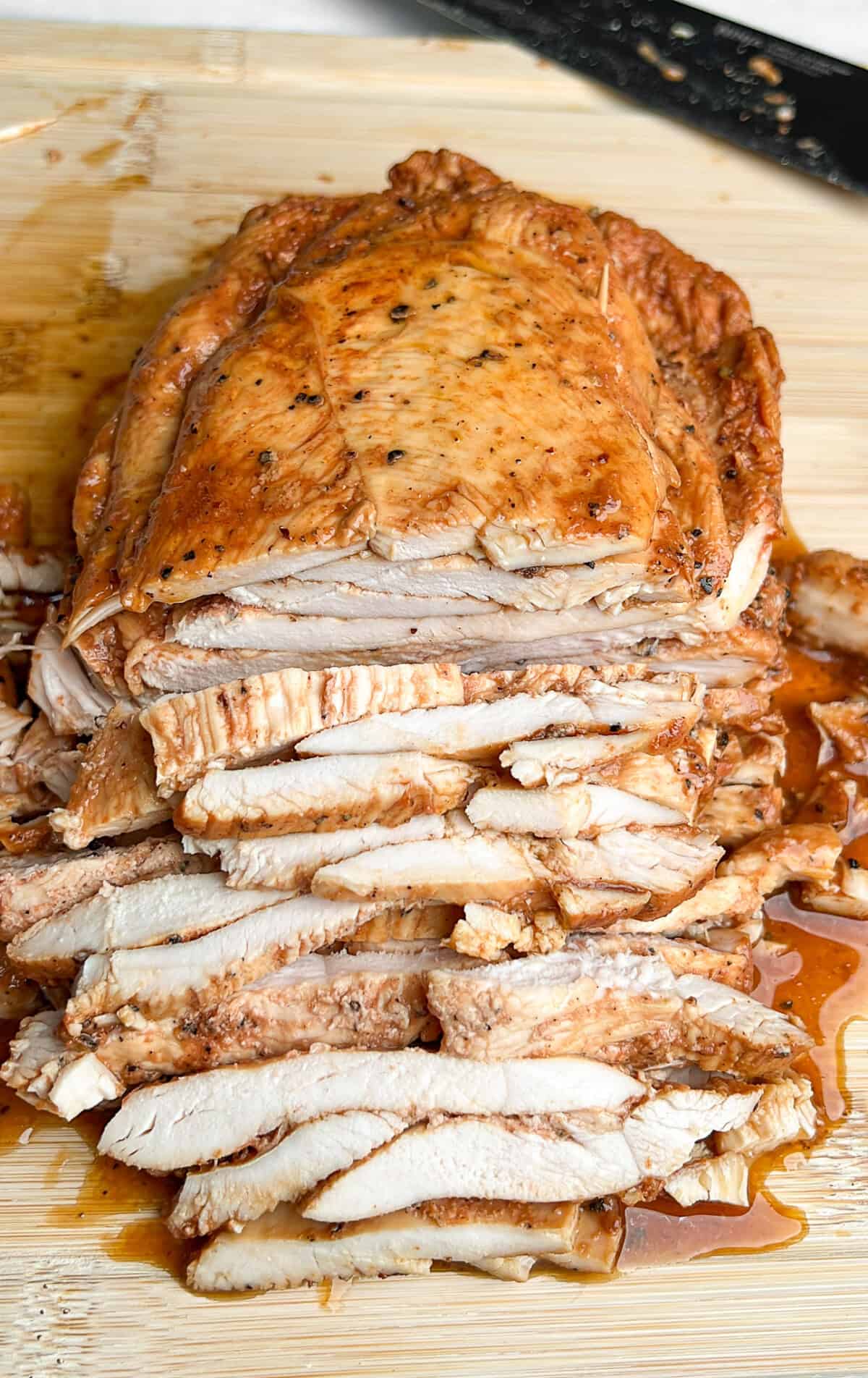 loaf pan chicken being sliced thin on a cutting board