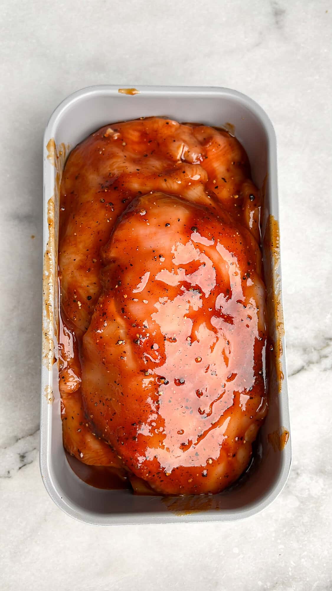 chicken coated in bbq sauce stacked in a loaf pan