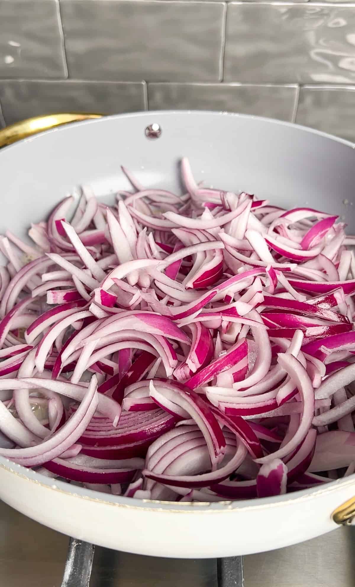 raw red onion slices in a pan with butter and olive oil