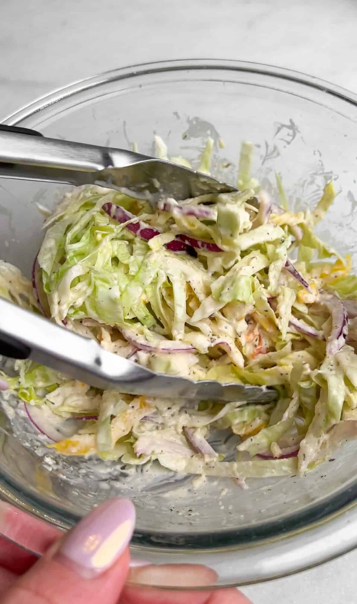 tossing the veggies in the grinder dressing in a bowl.