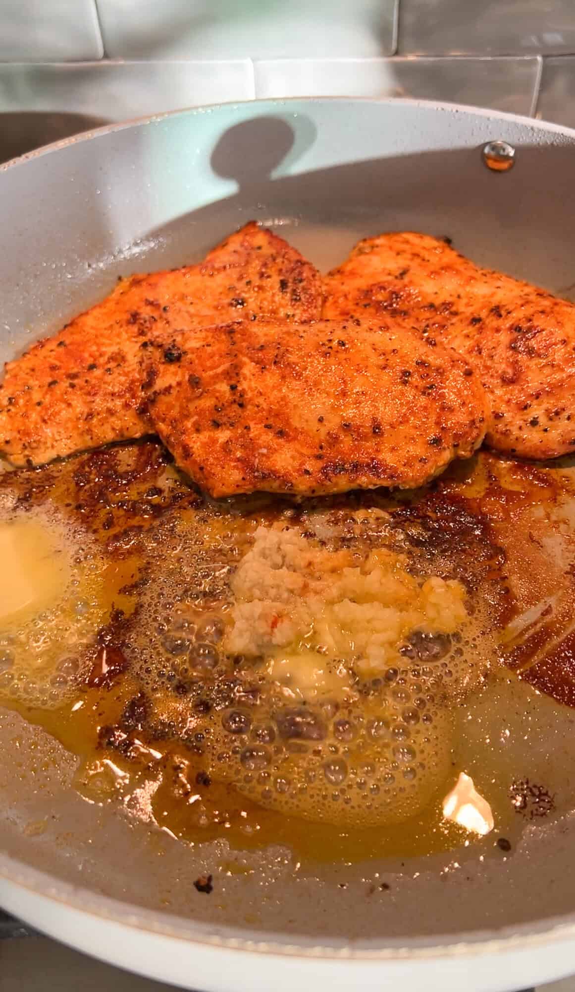 chicken in a pan being tossed in butter and garlic and ginger
