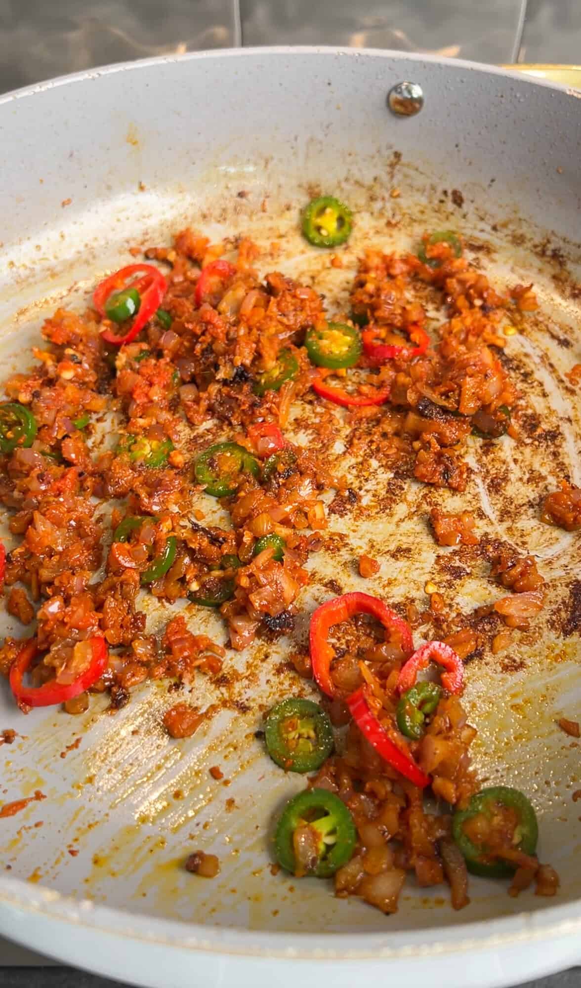aromatics mixed with red curry paste in a pan