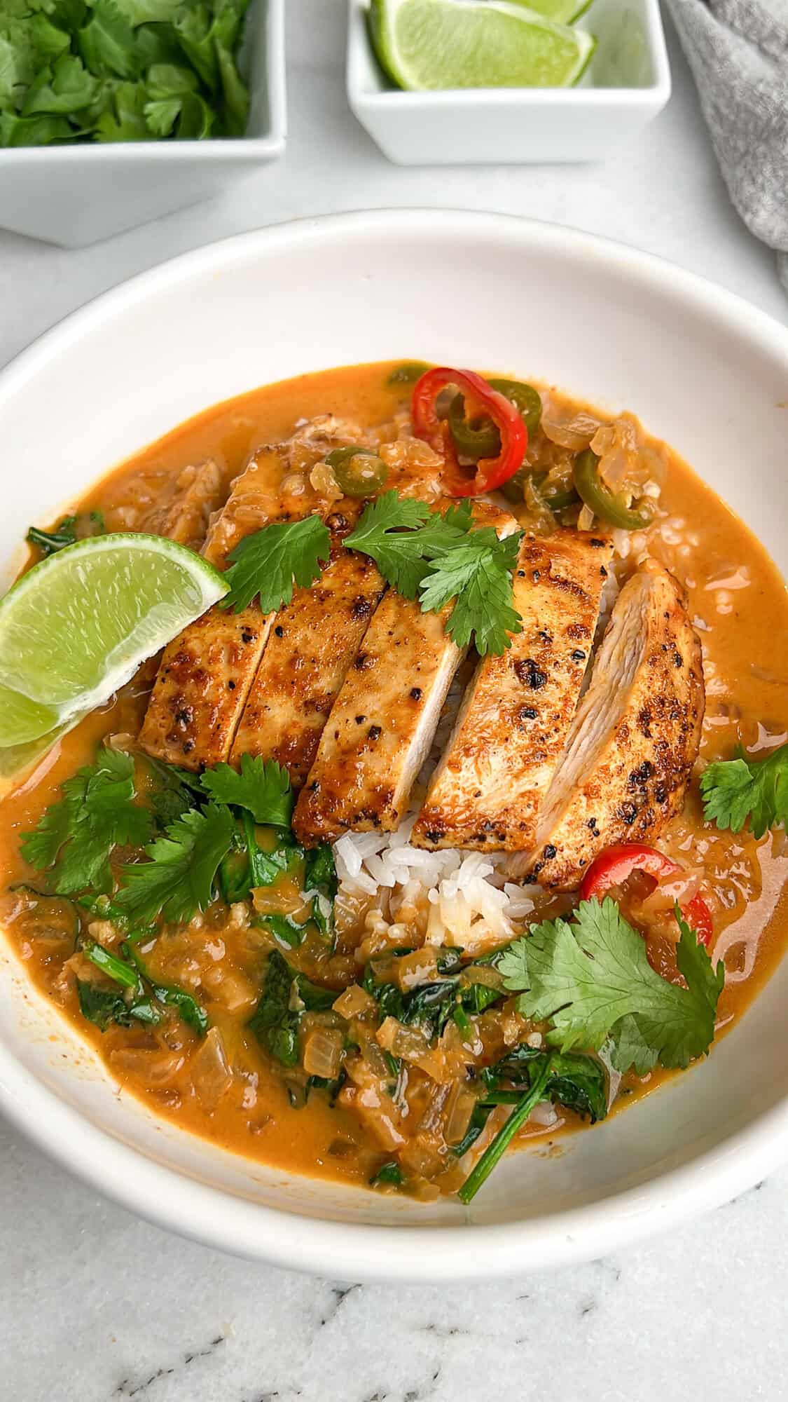 Thai coconut brothy rice in a bowl with lime, cilantro and basil