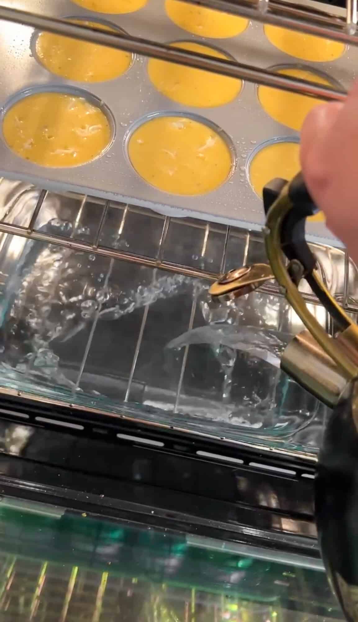 boiling water being added to the pan in the oven