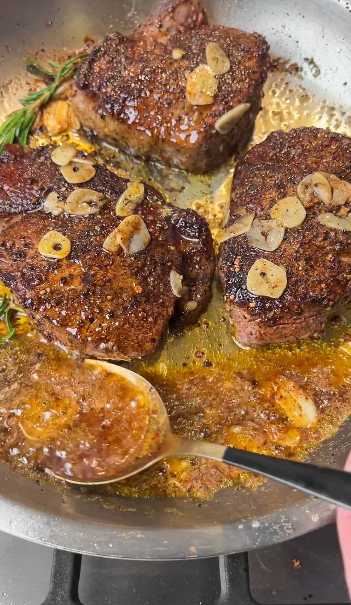Basting steaks with butter in a pan