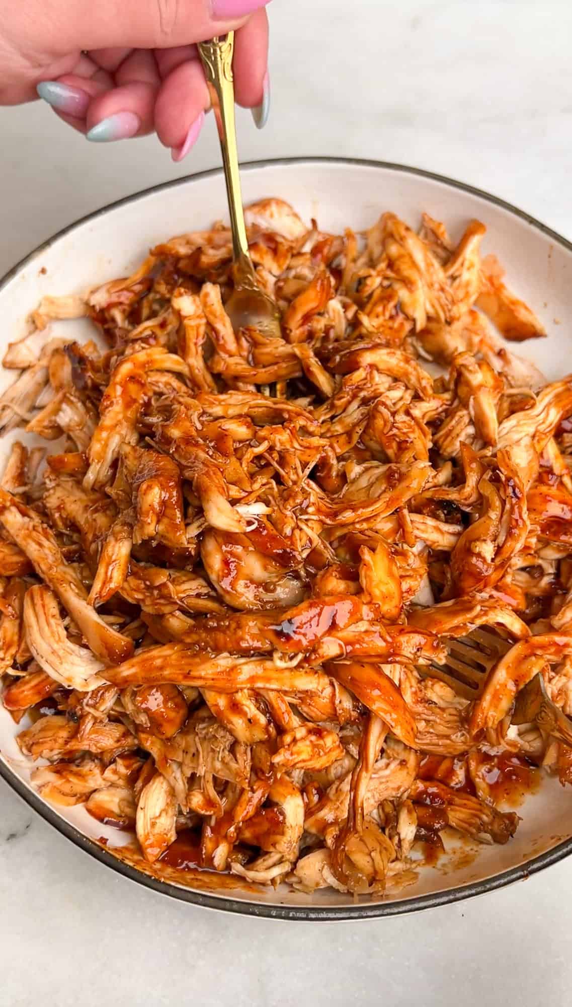 tossing the shredded chicken with bbq sauce