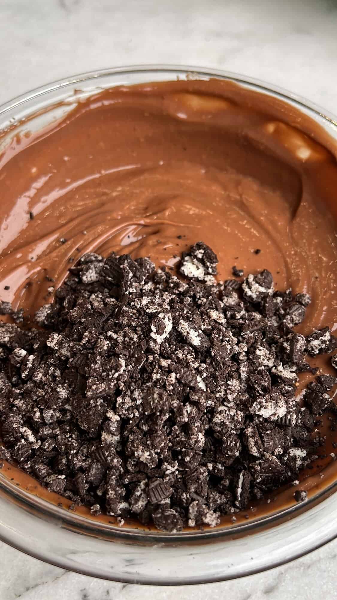 Oreo delight has an Oreo crust with creamy, no-bake layers of ganache, cream cheese, pudding, and whipped cream. An easy make-ahead dessert! Crushed Oreos added to chocolate pudding.