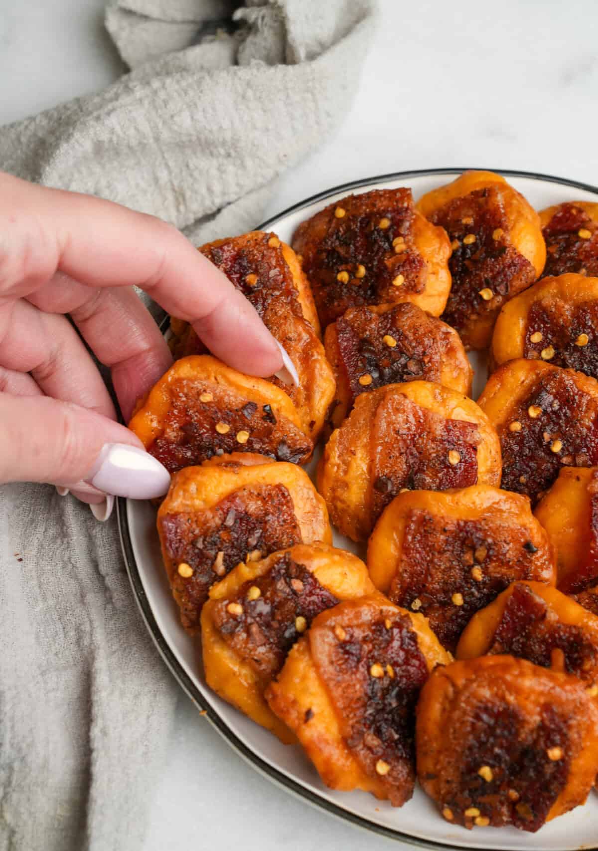 a plate for cheddar bacon crackers being grabbed by a hand
