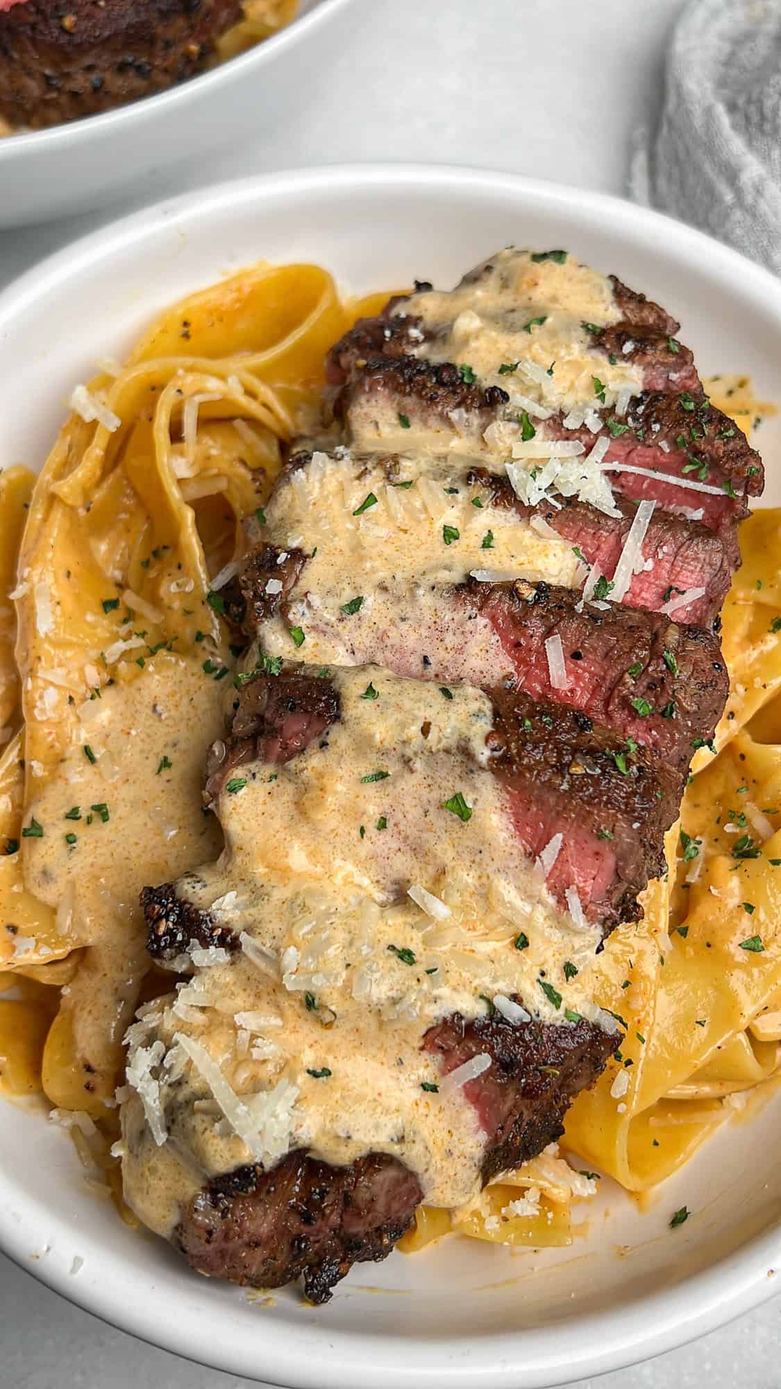 pasta in a bowl with steak and cream sauce on top