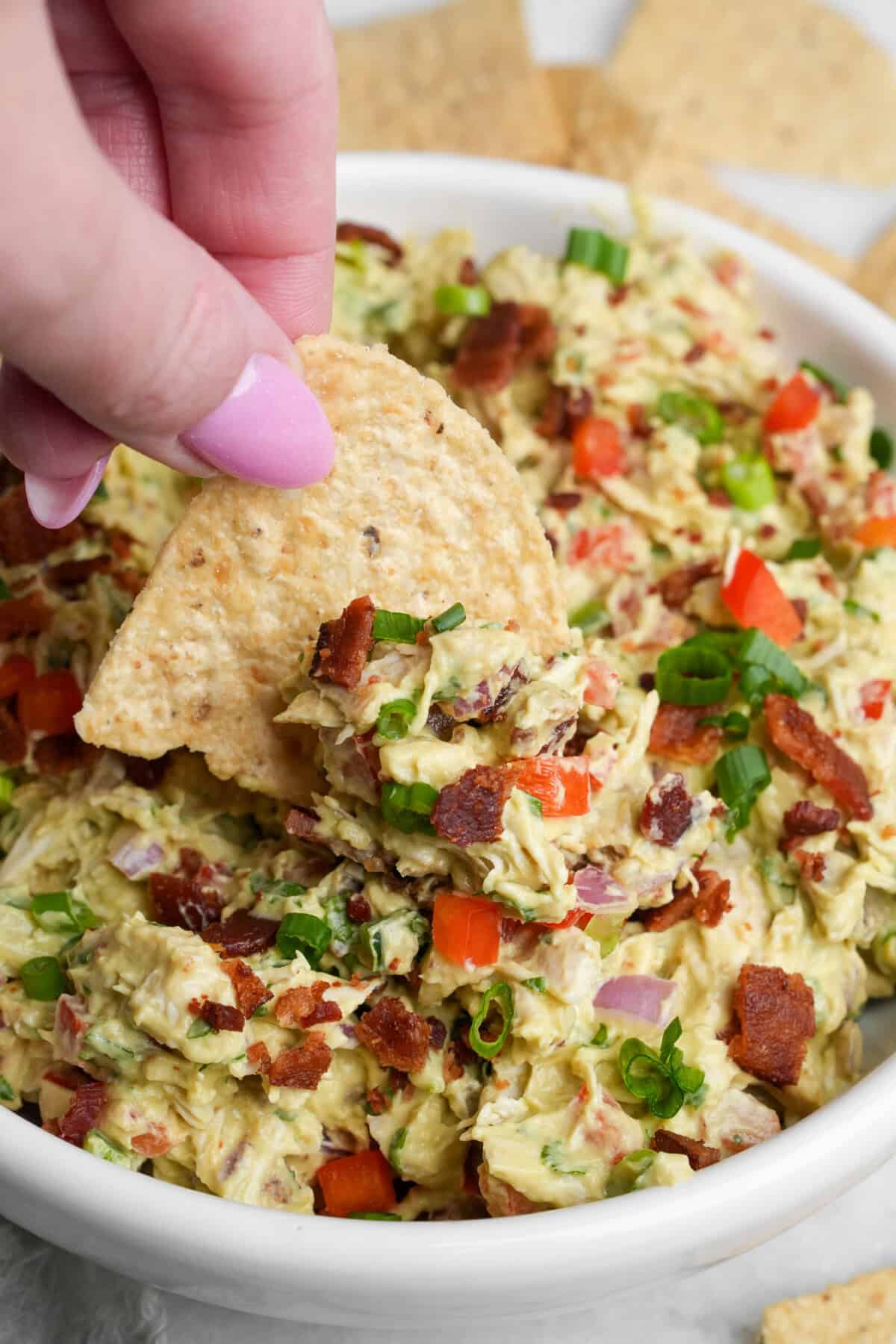 a tortilla chip digging into guacamole chicken salad