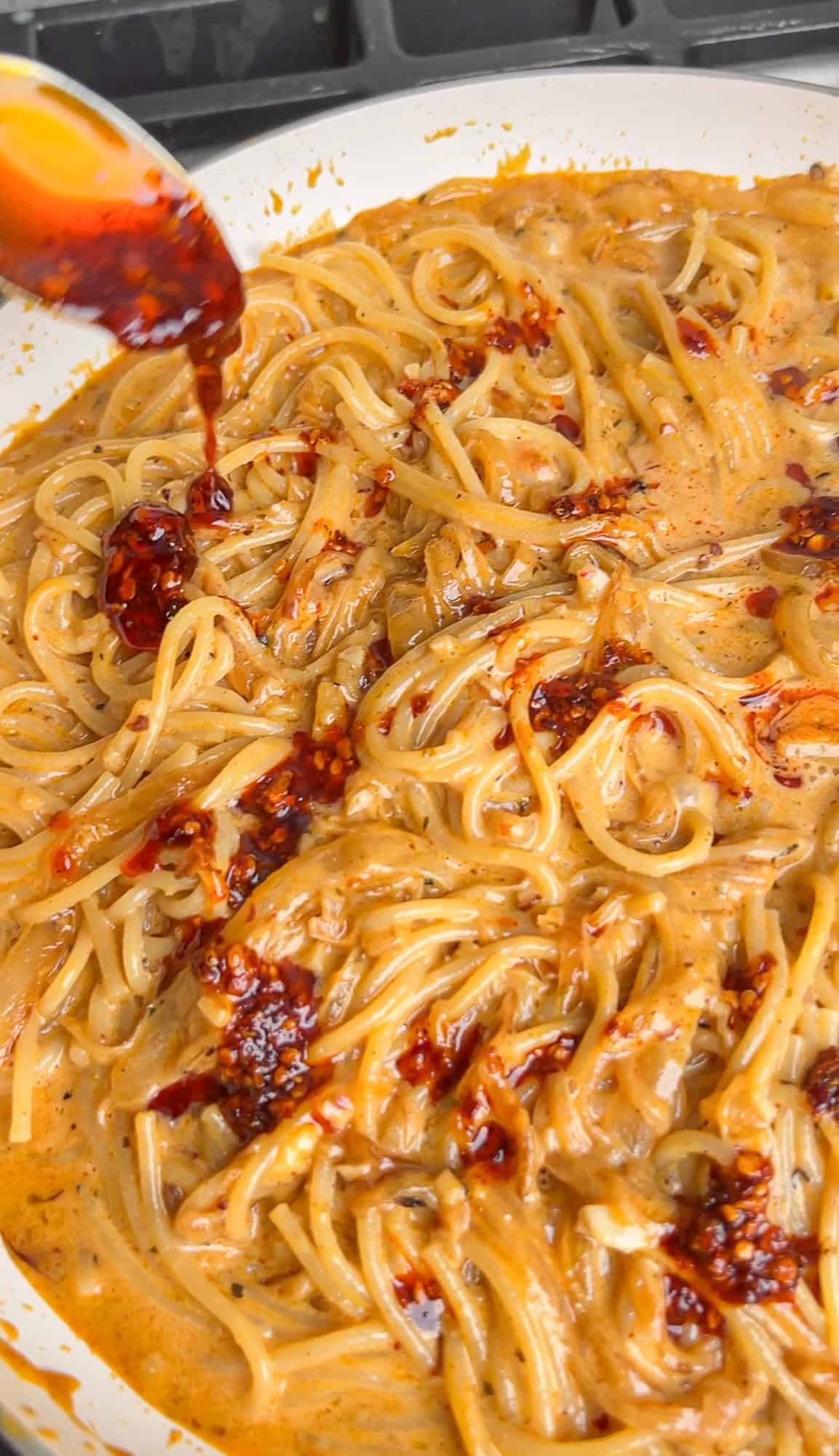 drizzling chili oil on caramelized onion pasta