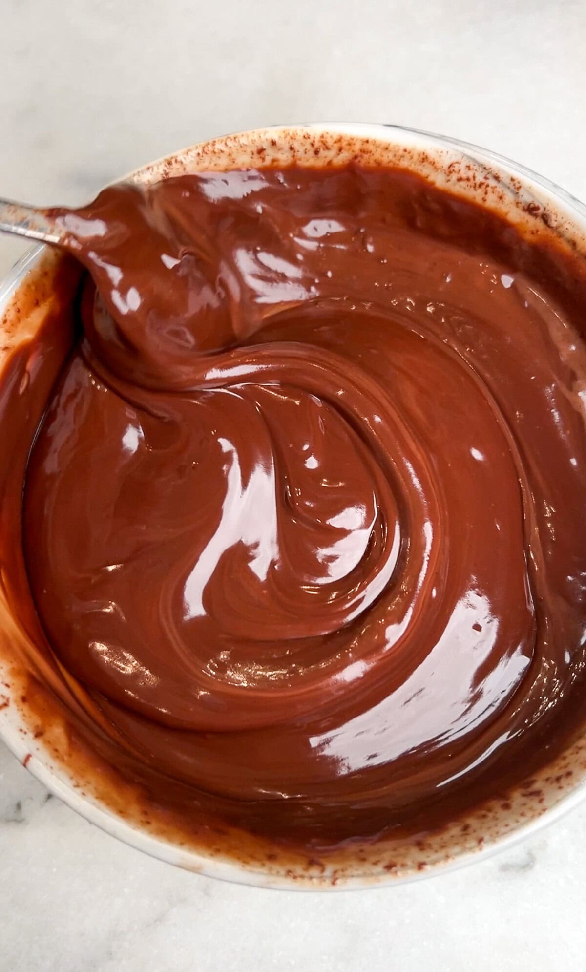 Oreo delight has an Oreo crust with creamy, no-bake layers of ganache, cream cheese, pudding, and whipped cream. An easy make-ahead dessert! Melted chocolate ganache in a bowl.
