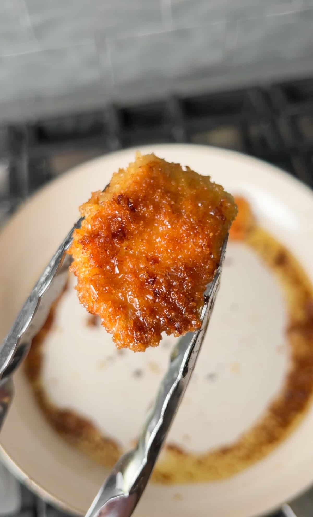 cooking the panko chicken in a pan for caesar salad chicken bowls