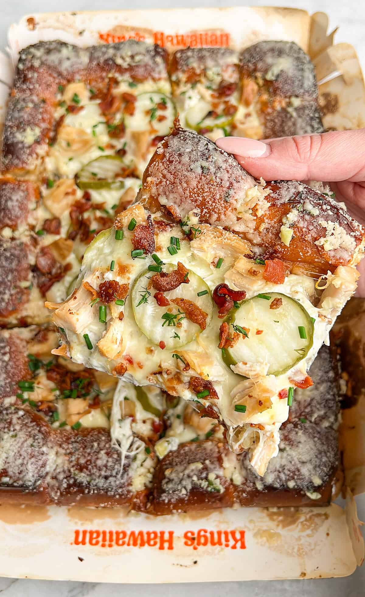 holding a slice of pickle pizza in hand