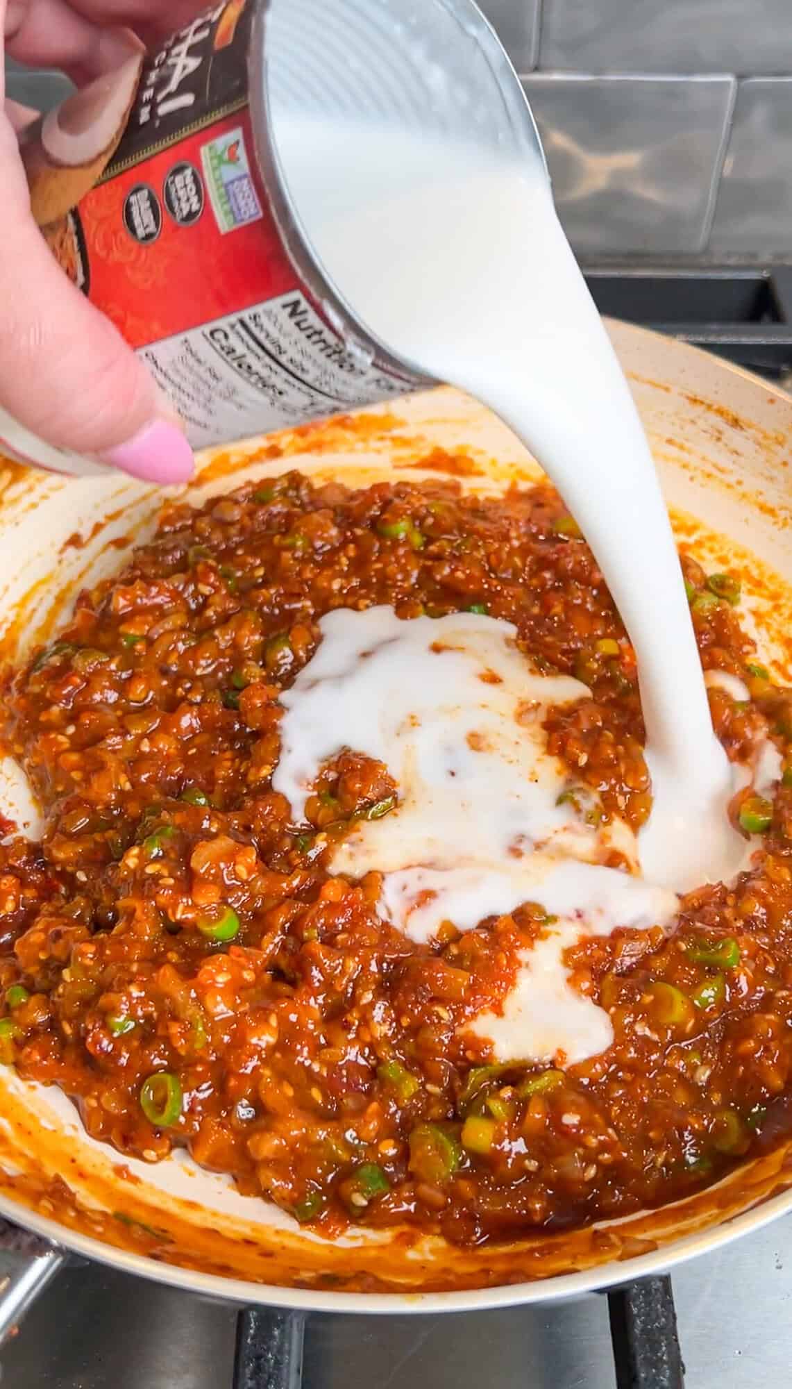 pouring coconut milk into the peanut butter sauce