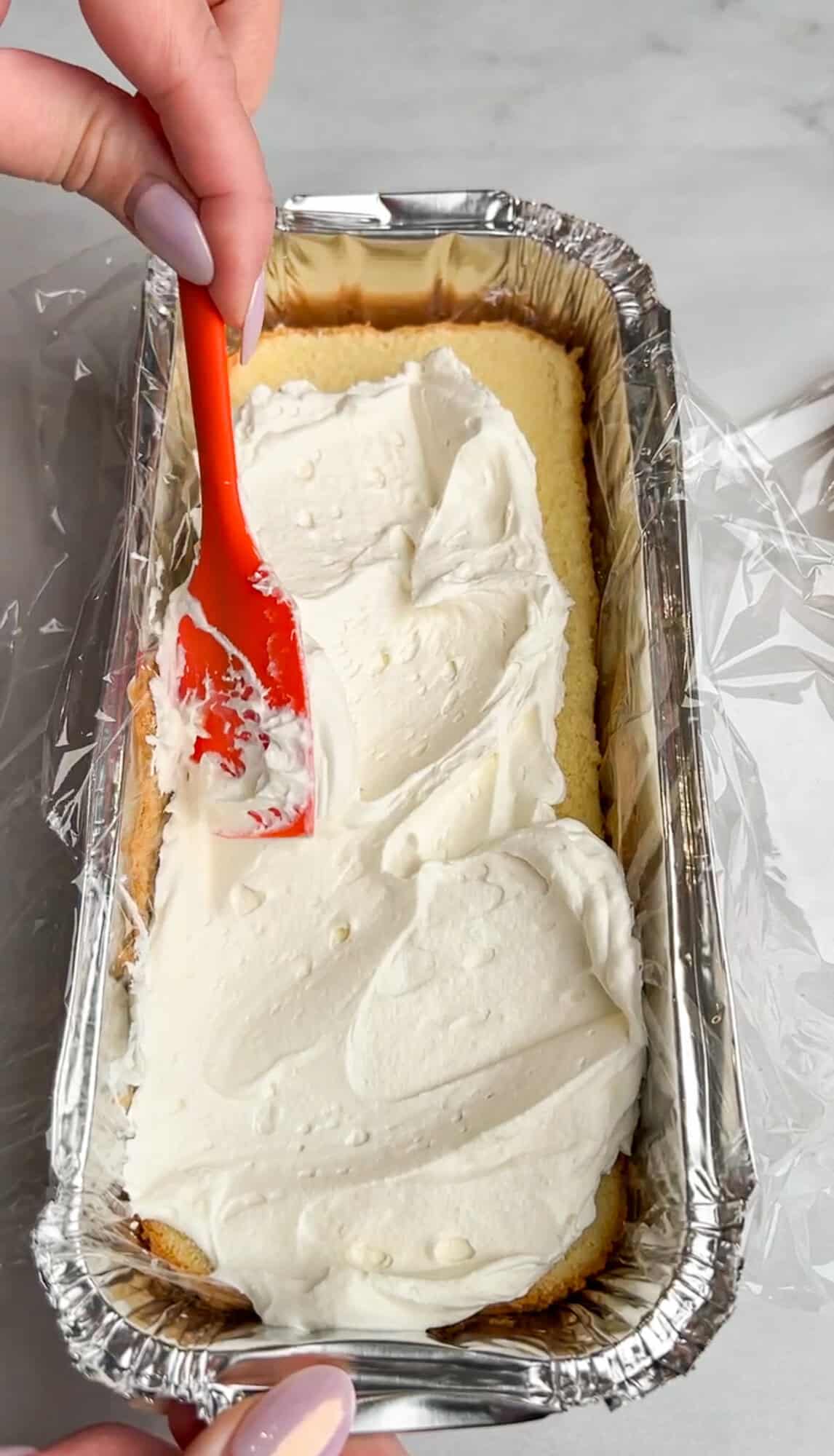 spreading whipped cream on the bottom of a poundcake