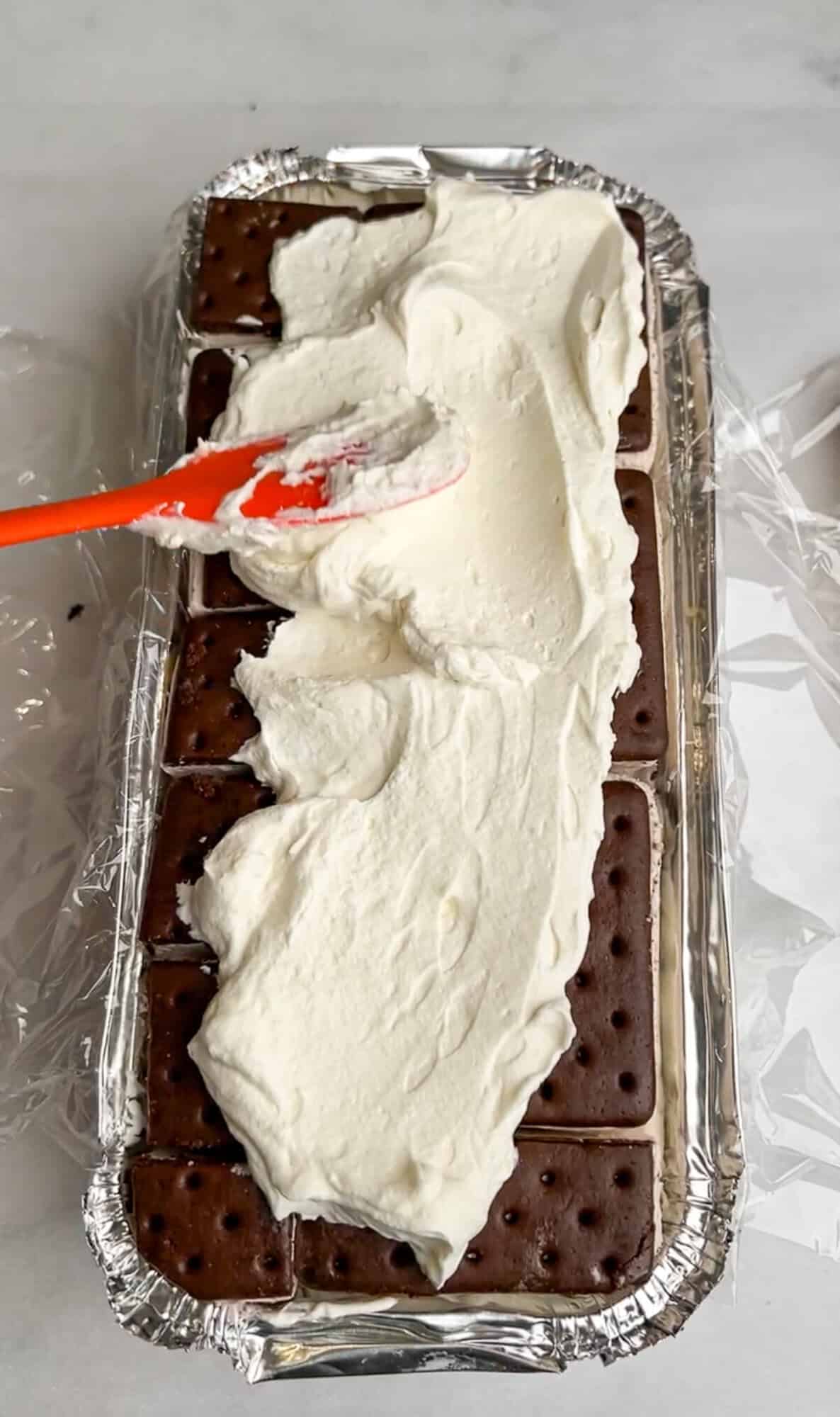 spreading whipped cream over ice cream sandwiches