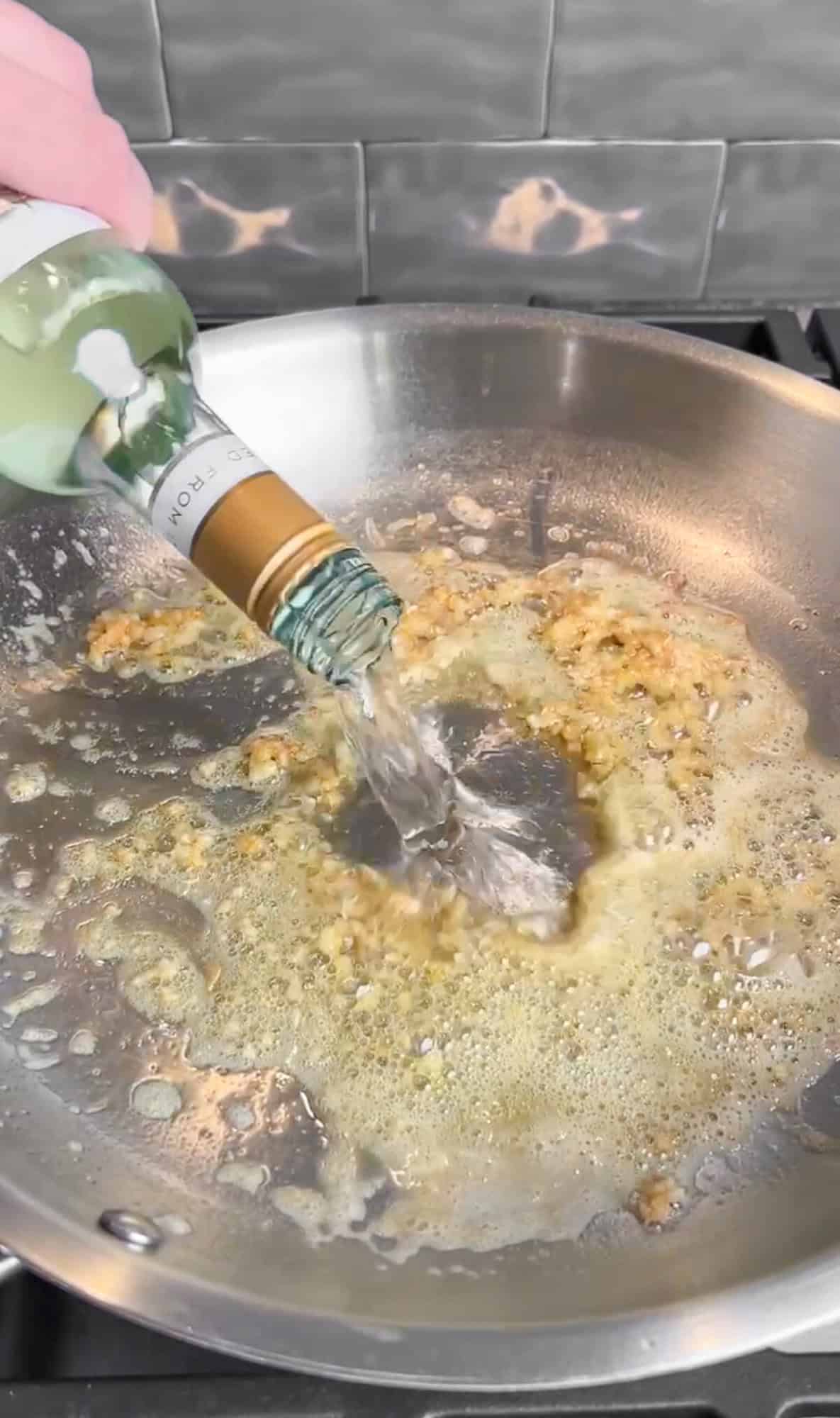 adding white wine to creamy lemon pasta