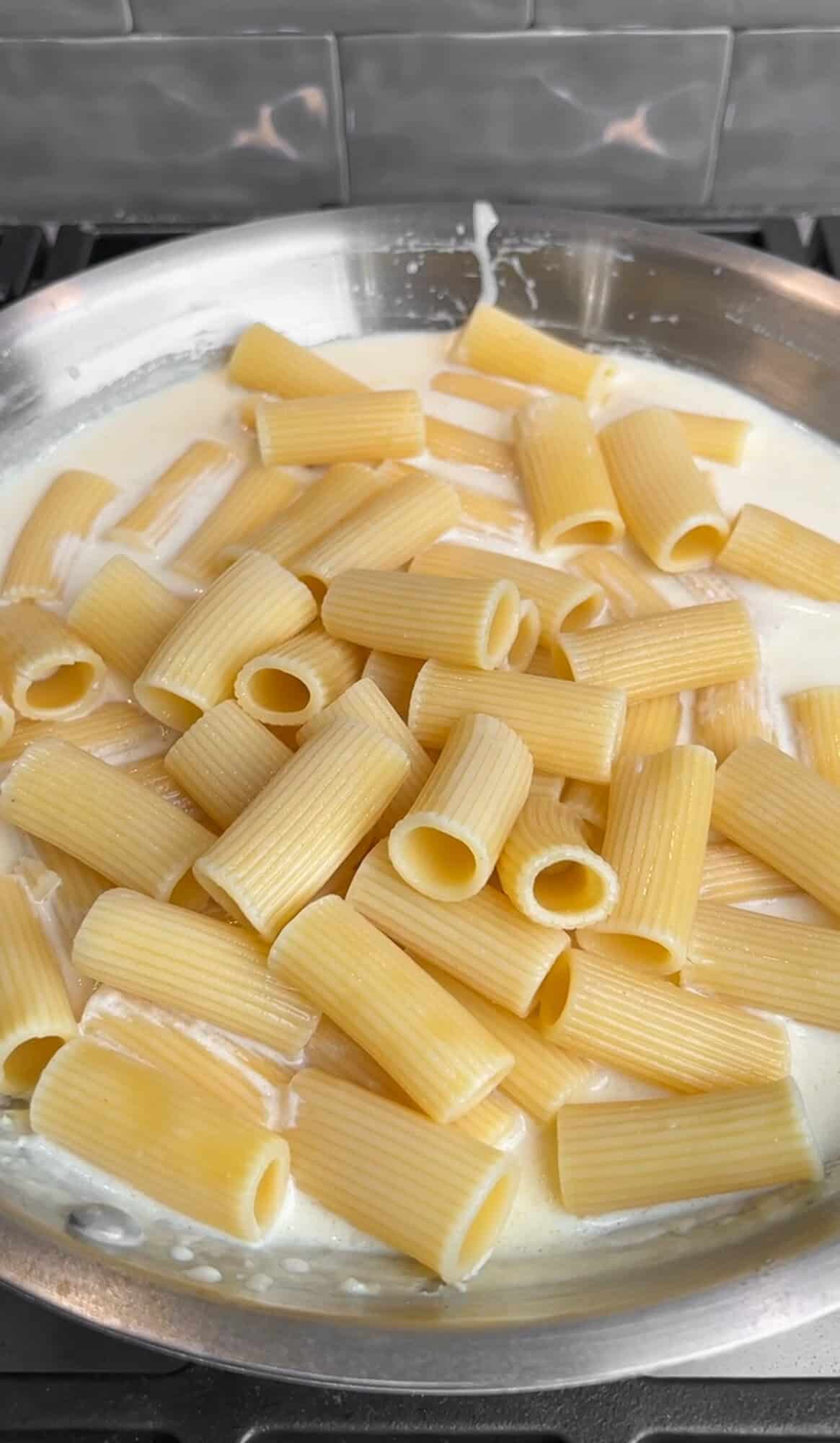 rigatoni being added to the creamy lemon pasta sauce