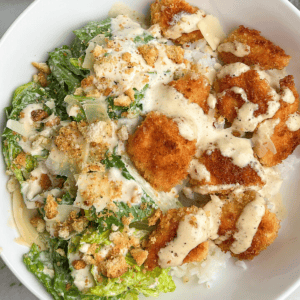 a rice bowl with chicken, salad and dressing