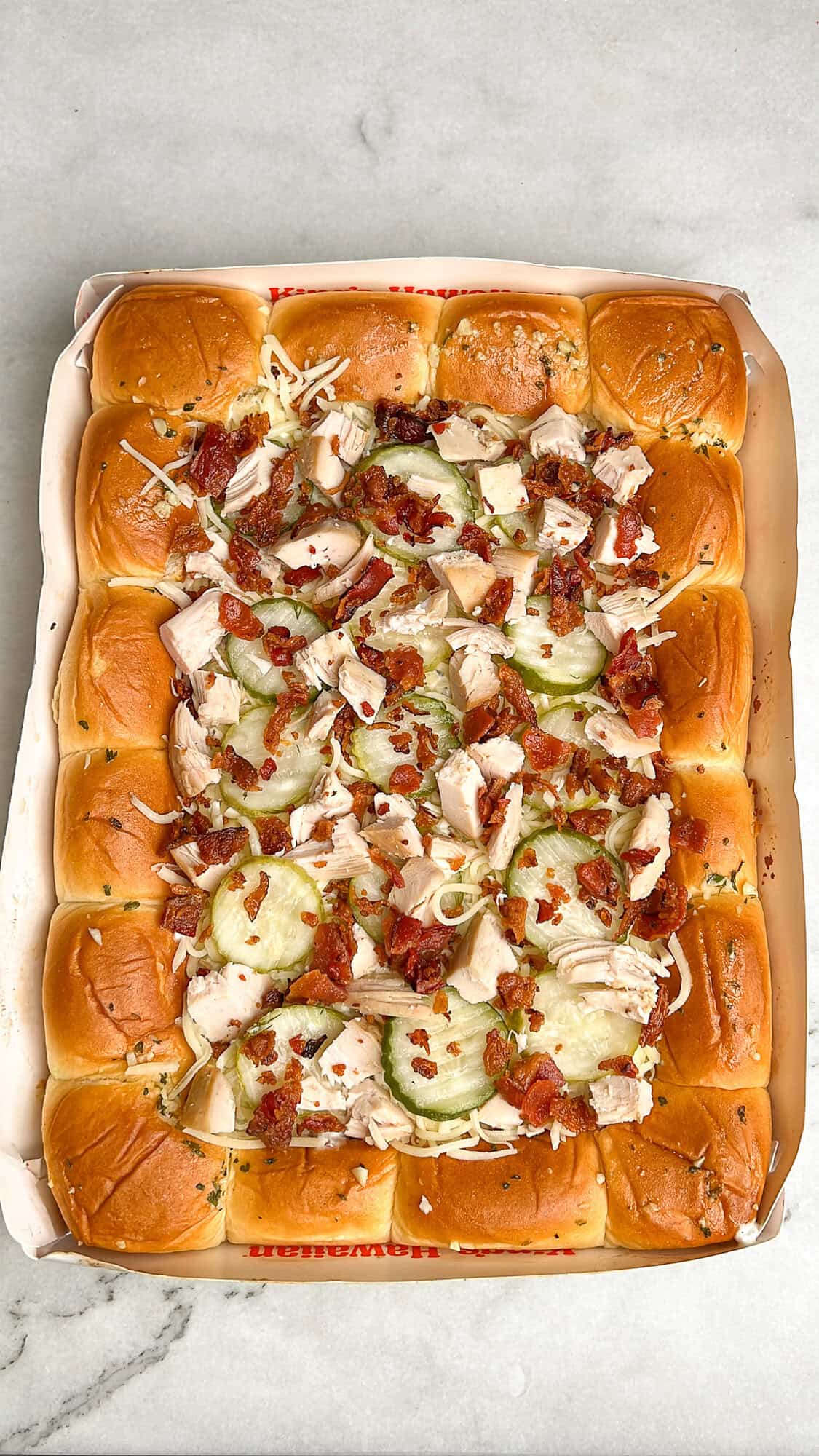 pickle pizza on hawaiian rolls topped with pickles, chicken, bacon, and mozzarella