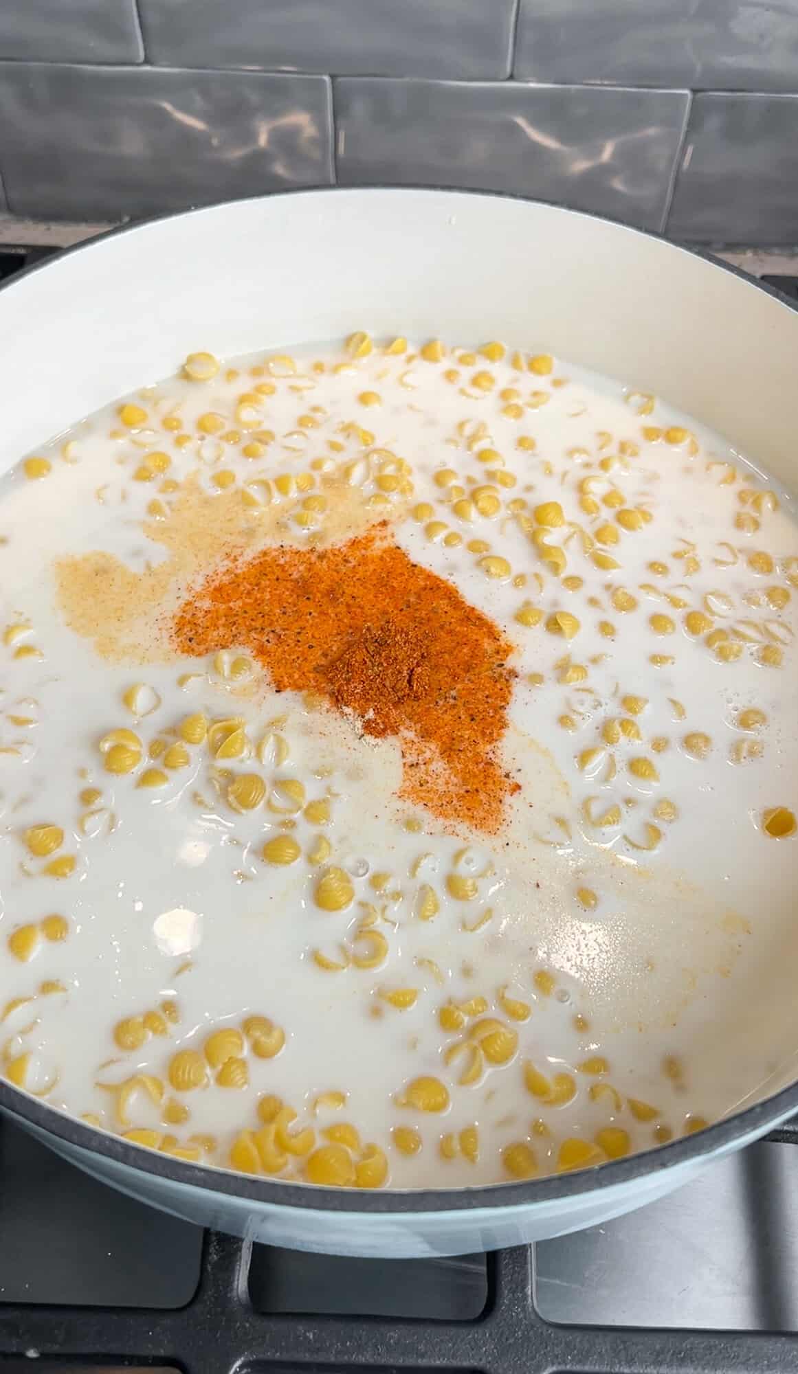 adding pasta, broth, cream, and seasonings into a pot