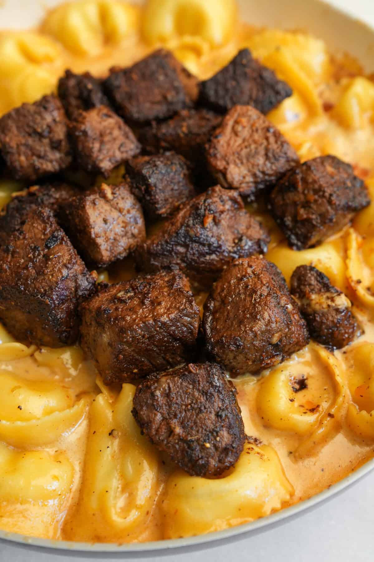 steak piled on creamy alfredo tortellini