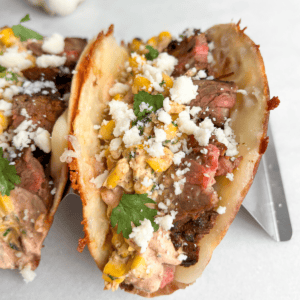 Carne asada tacos topped with street corn in taco holders