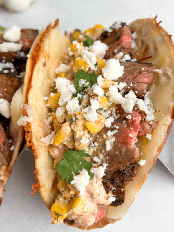 Carne asada tacos topped with street corn in taco holders