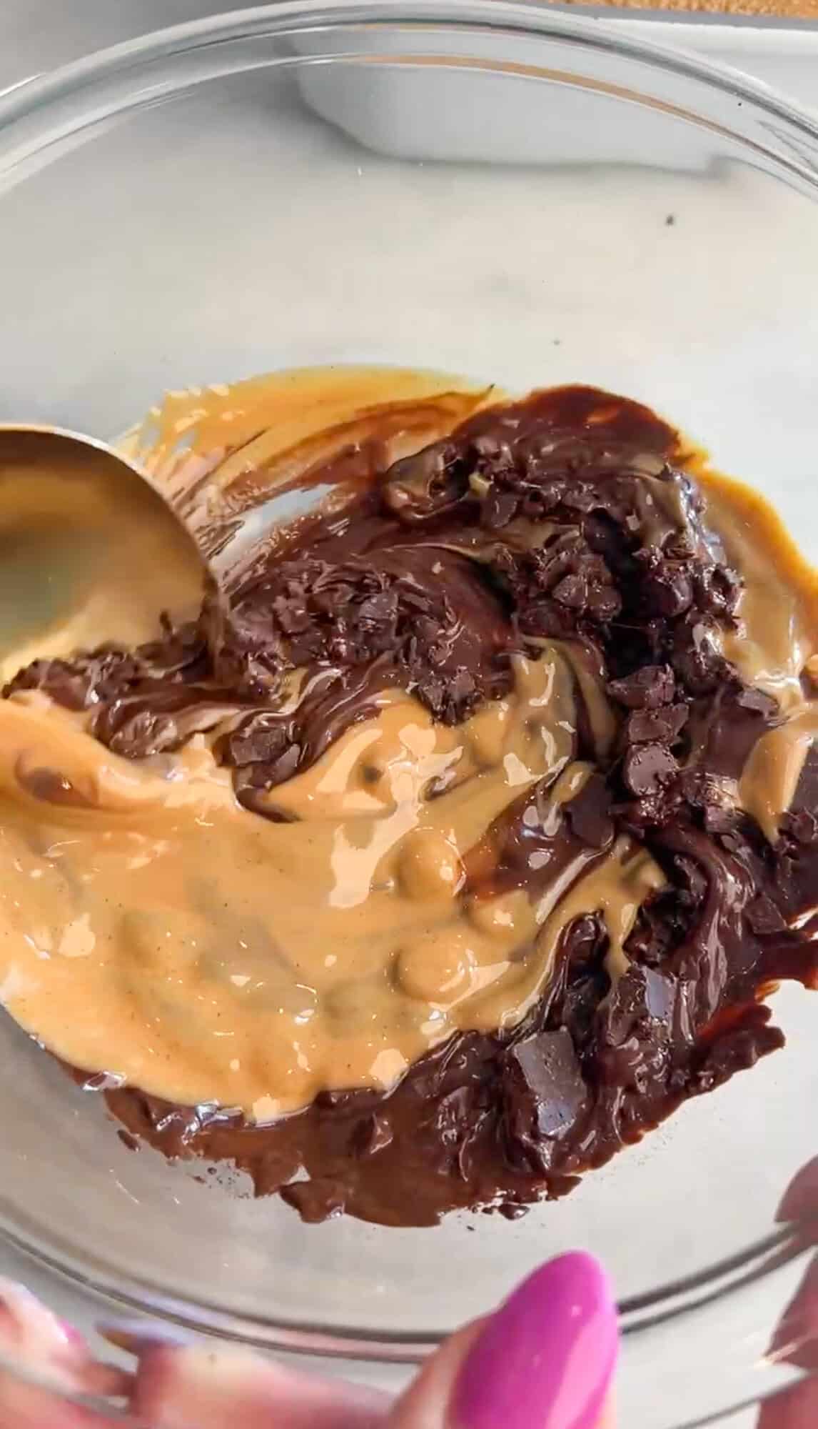 These no-bake peanut butter bars have a soft, sweet peanut butter base and a rich chocolate top with a sprinkle of flaky salt. Stirring peanut butter and melted chocolate together in a bowl.