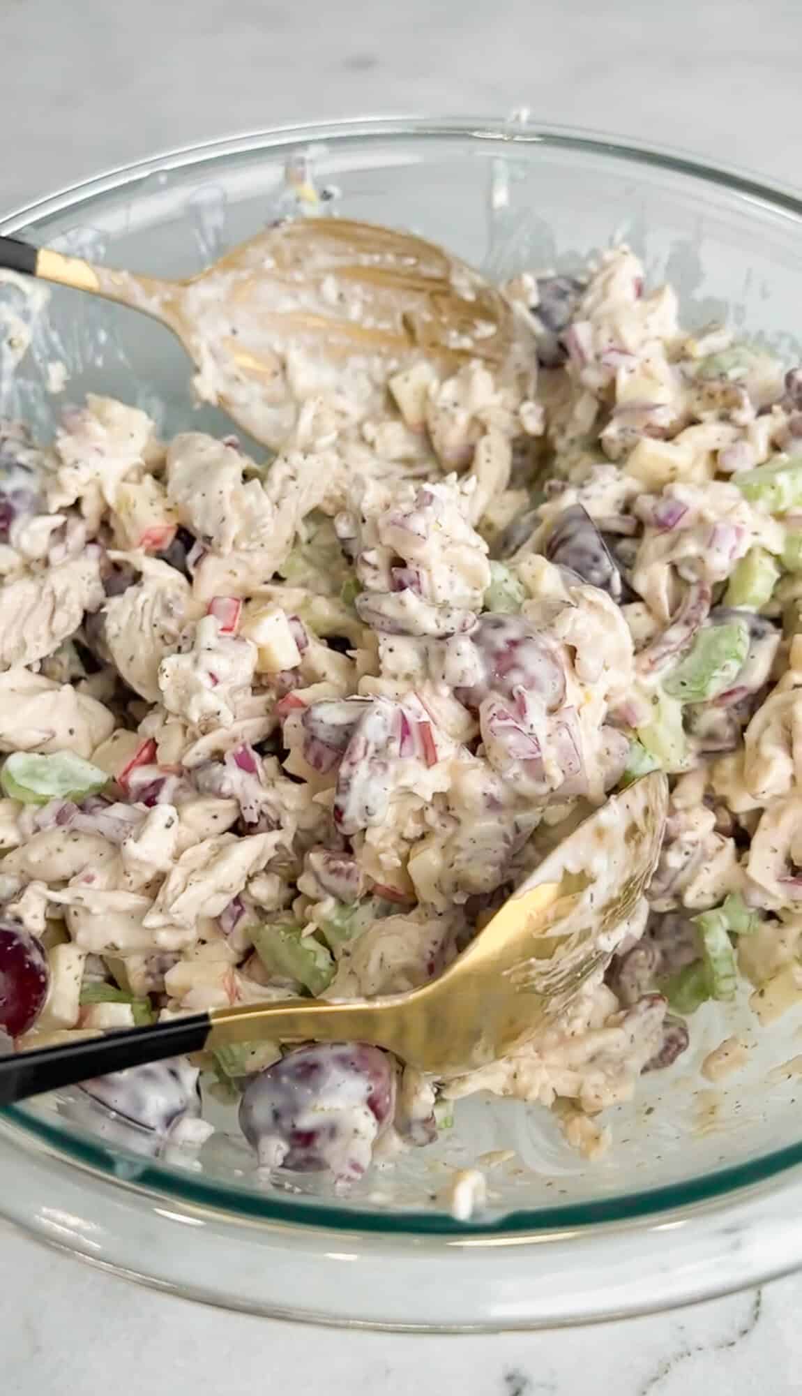 Tart grapes and apples, crunchy celery, red onion, pecans, and chicken are tossed in a creamy lemon dressing in this Waldorf Chicken Salad. Stirring Waldorf chicken salad with a spoon