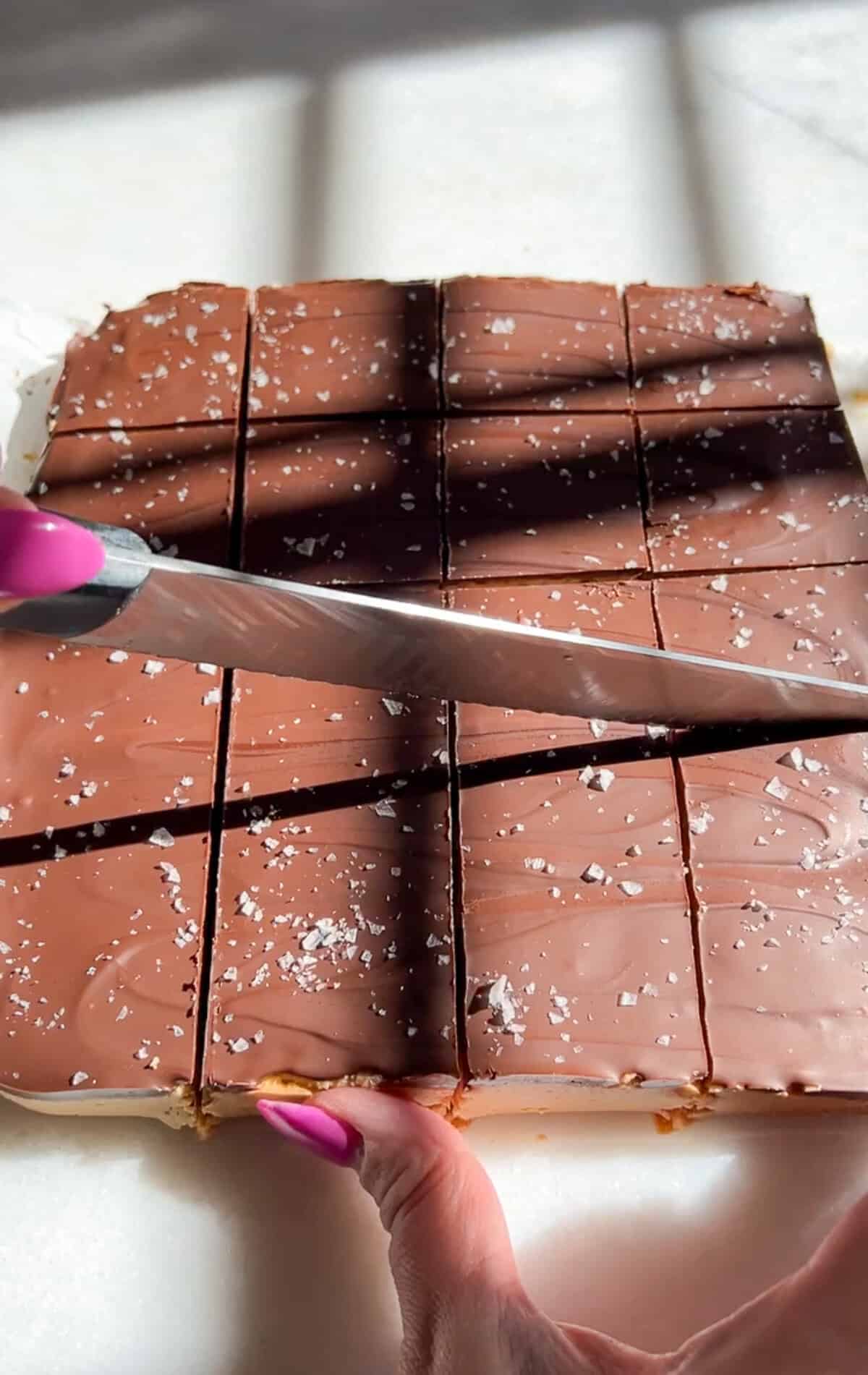 These no-bake peanut butter bars have a soft, sweet peanut butter base and a rich chocolate top with a sprinkle of flaky salt. Slicing the chocolate peanut butter bars