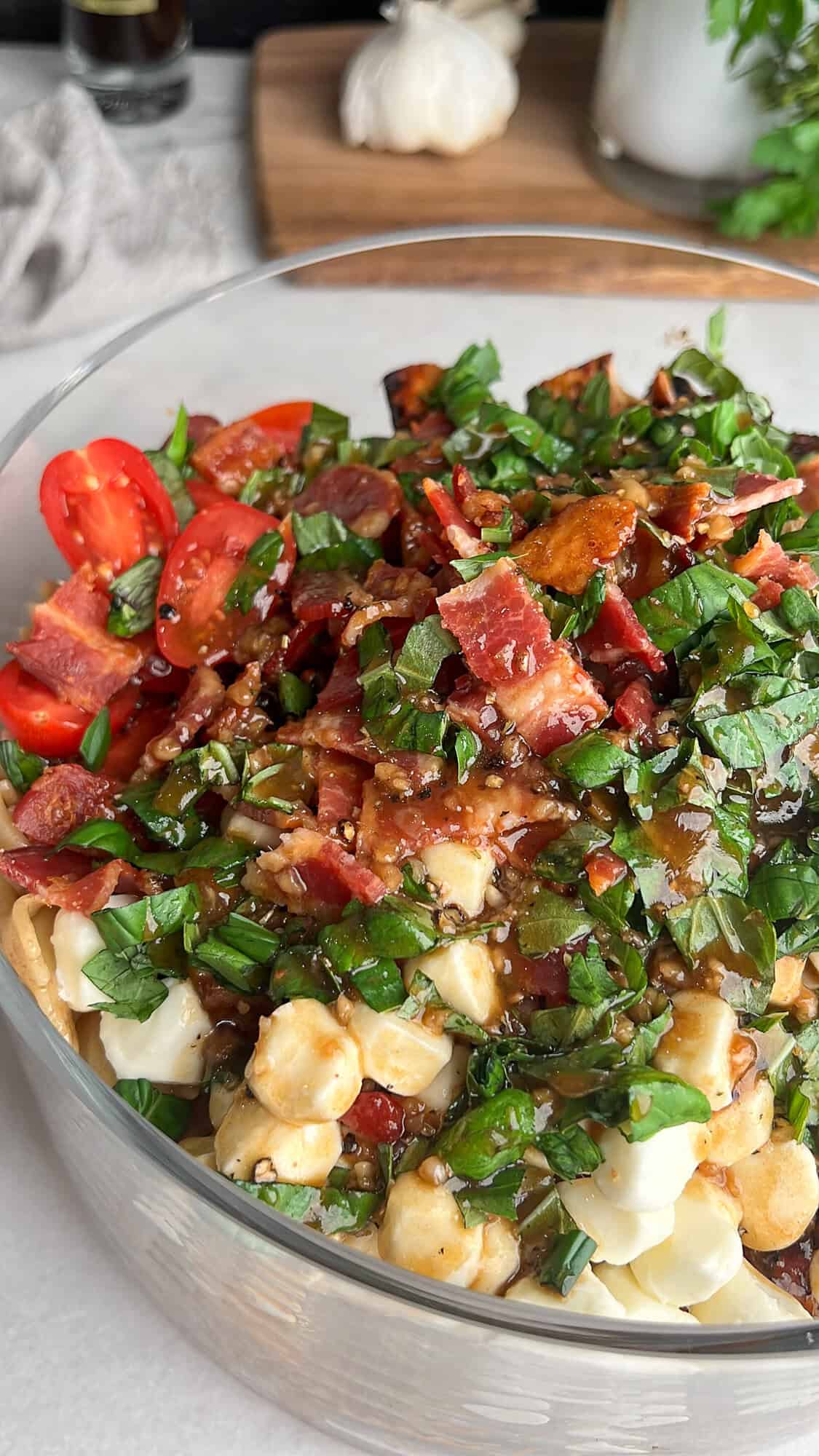 Caprese Pasta Salad is loaded with marinated chicken, tomatoes, mozzarella pearls, bacon, and basil tossed in a tangy balsamic dressing. Caprese pasta salad in a bowl