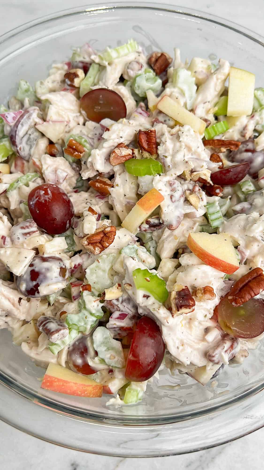 Tart grapes and apples, crunchy celery, red onion, pecans, and chicken are tossed in a creamy lemon dressing in this Waldorf Chicken Salad. Overhead view of a bowl of Waldorf chicken salad