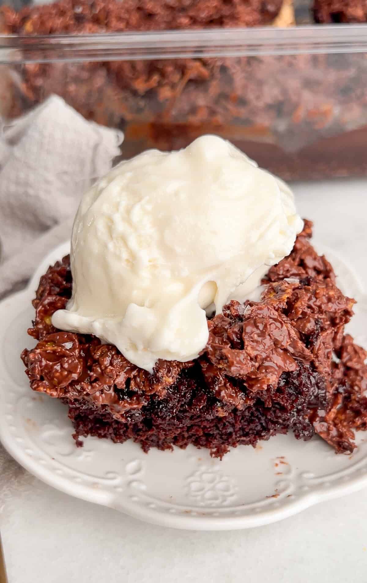 A serving of chocolate crunch cake on a white plate with ice cream