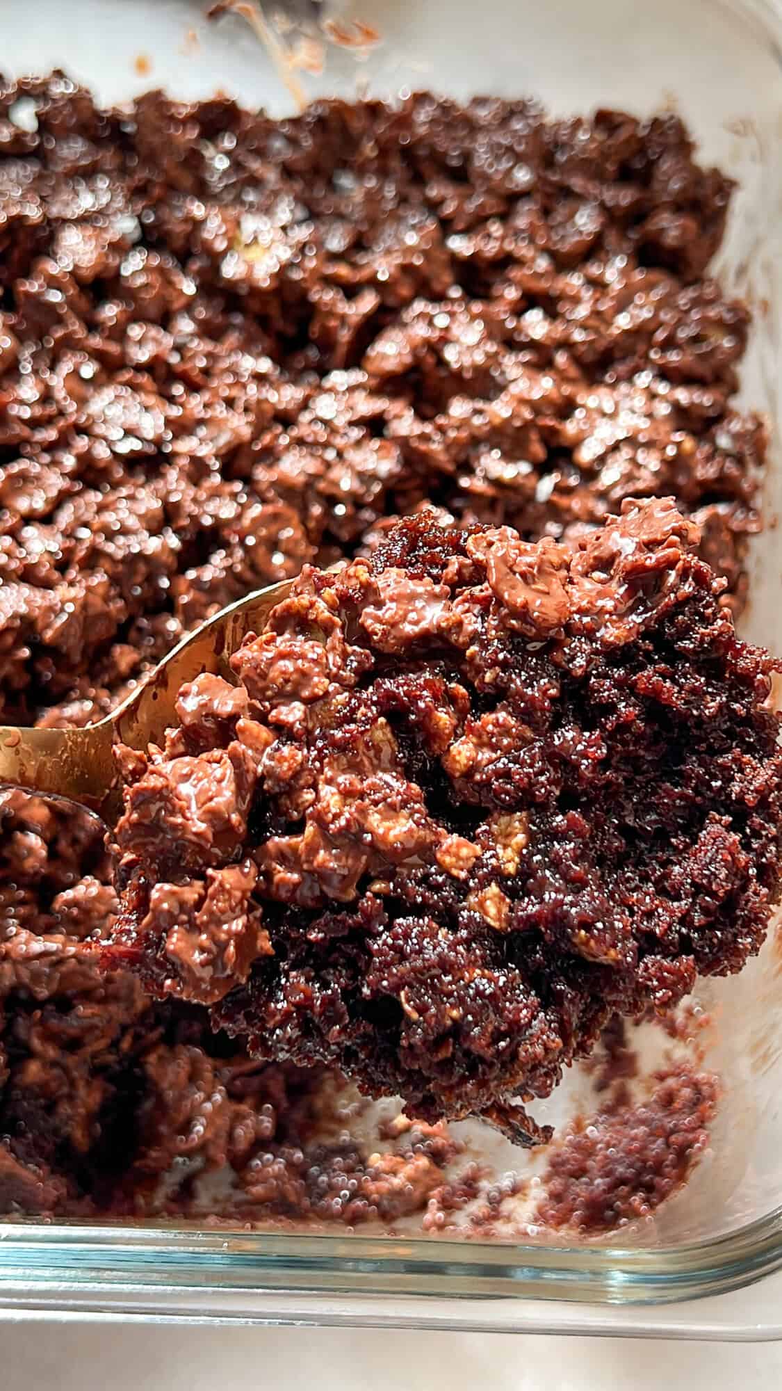 A spatula raising a slice of chocolate crunch cake from the cake pan