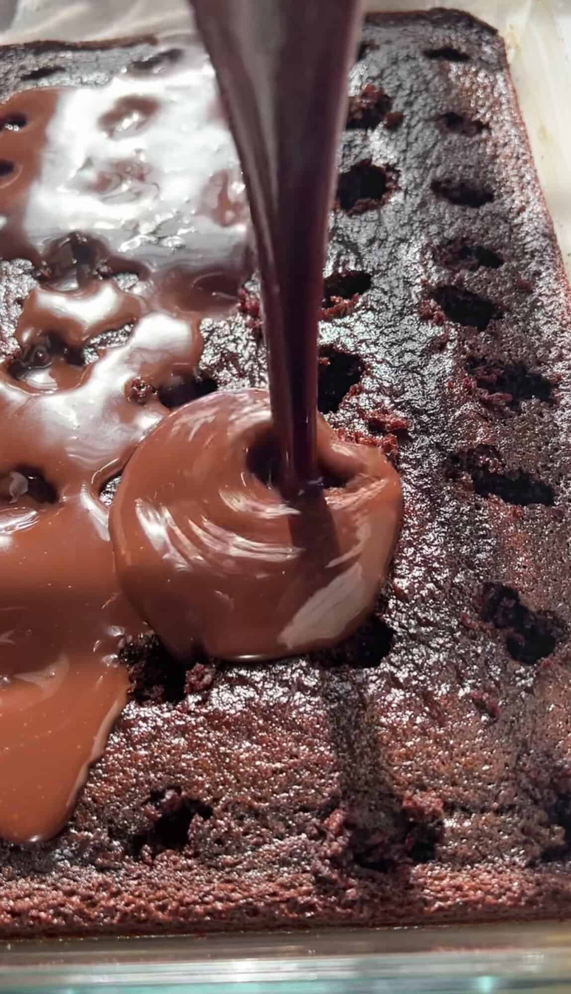 Pouring melted Nutella over the holes in a chocolate cake