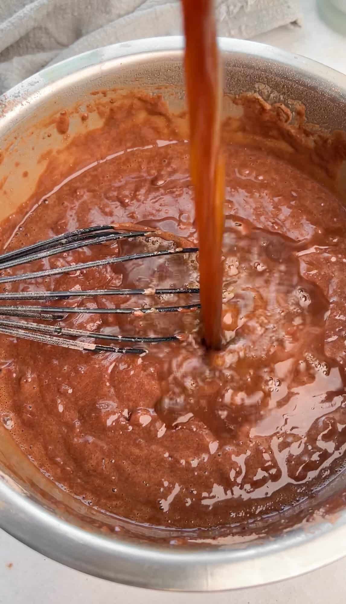 Pouring hot coffee into chocolate cake batter.