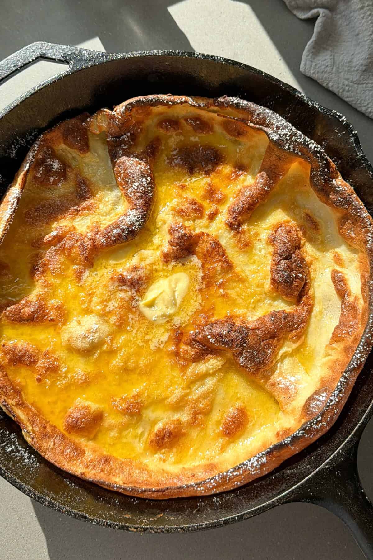dutch baby pancake with whipped butter in a cast iron skillet