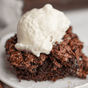 A slice of chocolate crunch cake on a white plate with ice cream