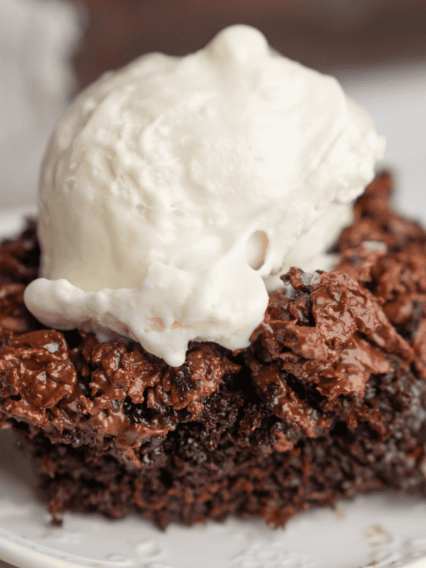 A slice of chocolate crunch cake on a white plate with ice cream