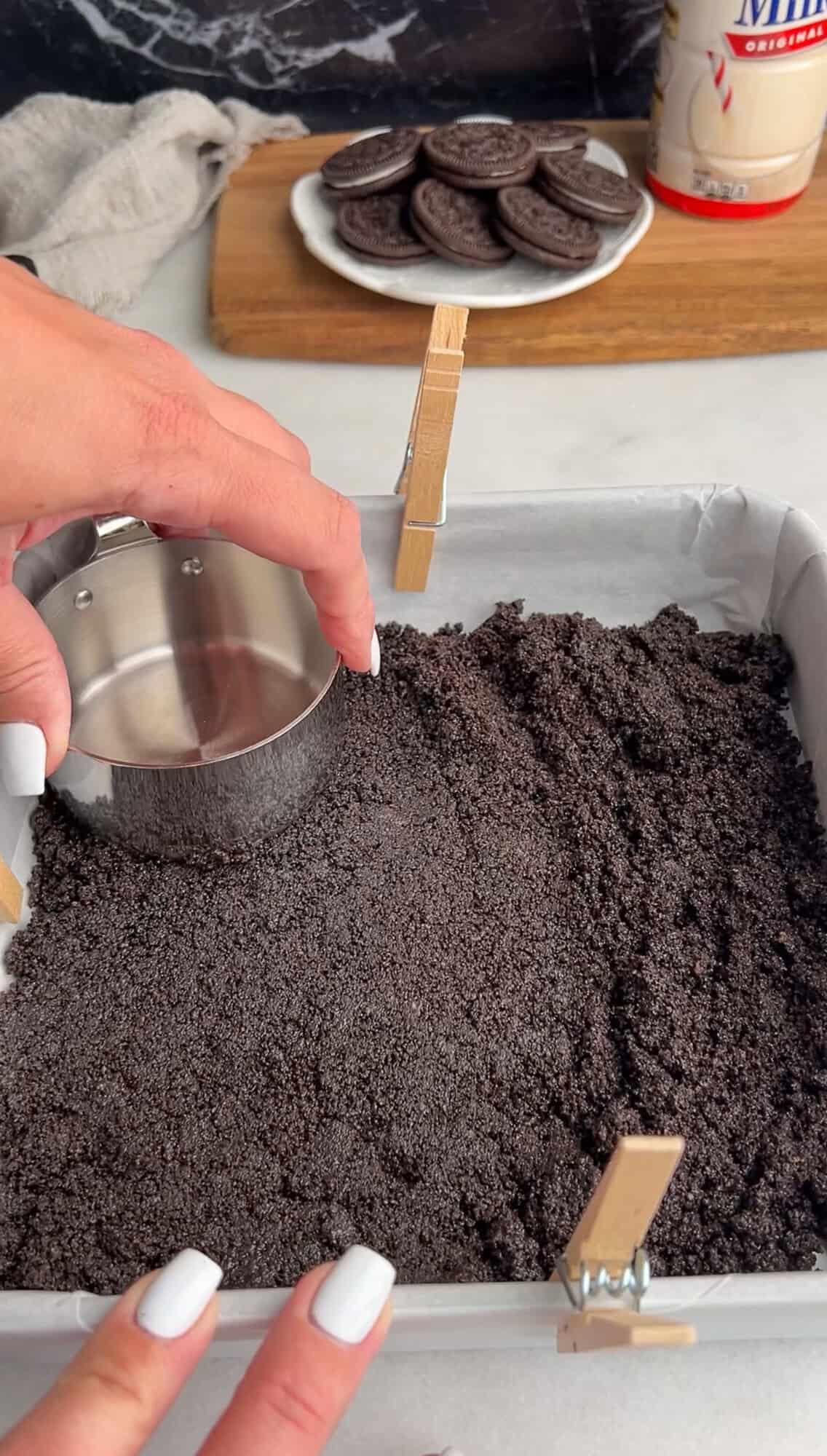 Pressing oreo crumbs into the 9x9 lined pan
