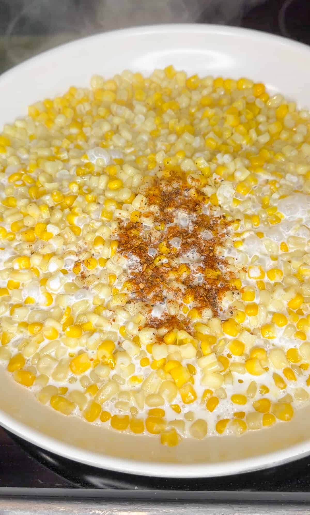 adding cajun seasoning to skillet corn dip