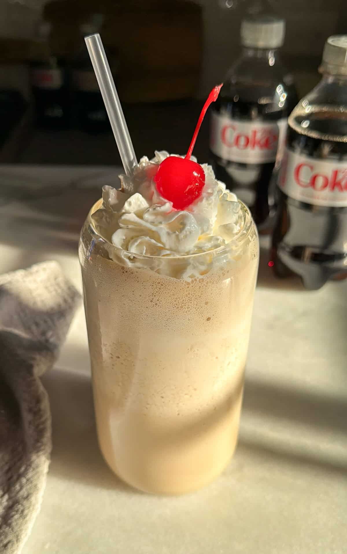 whipped diet coke in a glass with whipped cream and cherry