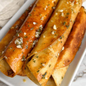 taquitos on a plate brushed with garlic butter
