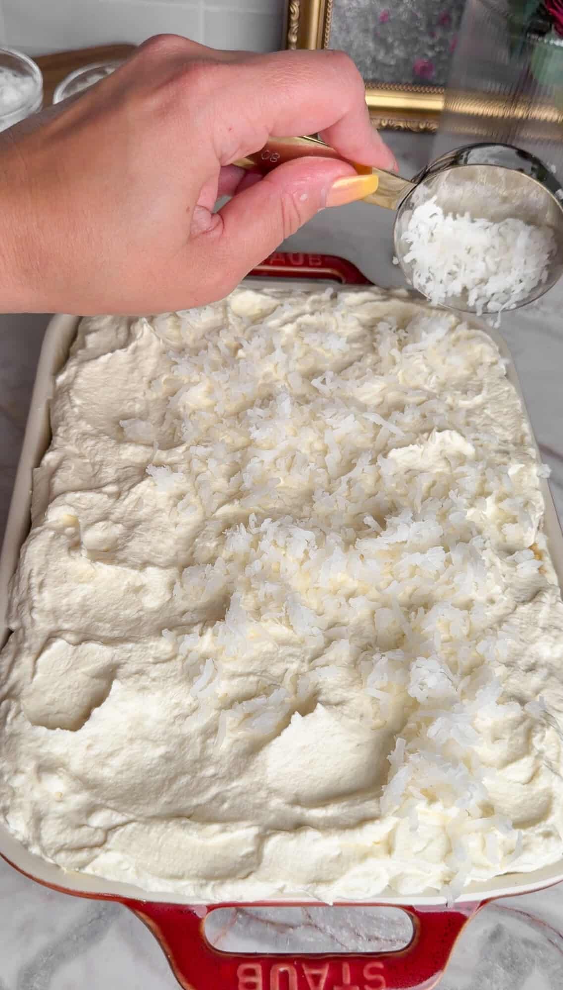 adding coconut topping to coconut cake